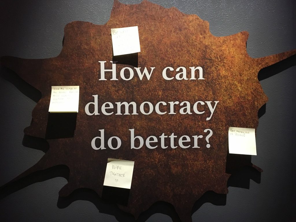 A sign that says 'how can democracy do better?'
