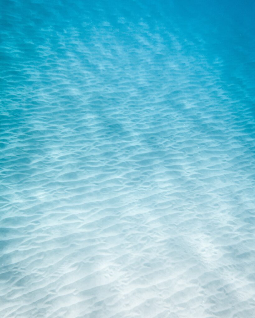 A photograph of the ocean, rippling in shades of light blue, white, and turquoise